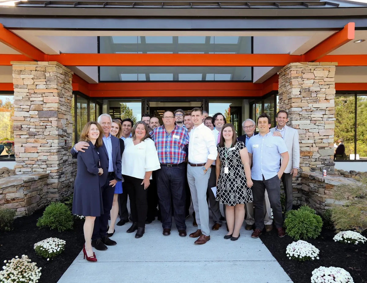 Greg LeMond, Nicolas Wegener and a group of colleagues outside a modern stone and steel building