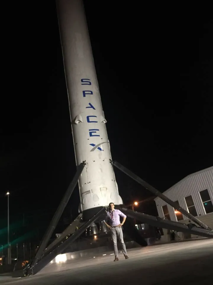Nicolas Wegener standing beneath the first recovered Falcon 9 first stage outside SpaceX headquarters in Hawthorne, California
